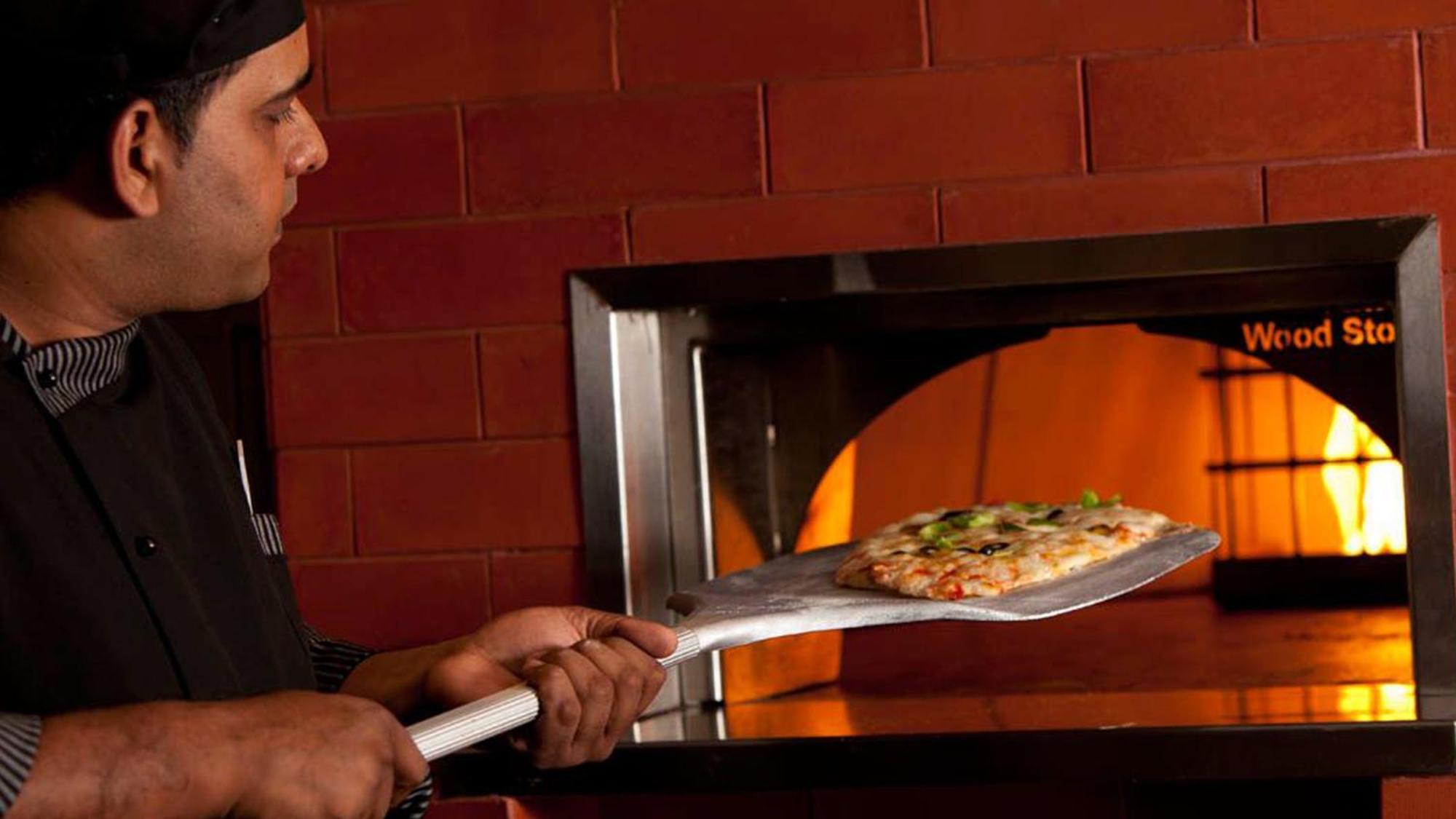 Holiday Inn Cochin By Ihg Kochi Zewnętrze zdjęcie Pizza being removed from a wood-fired oven
